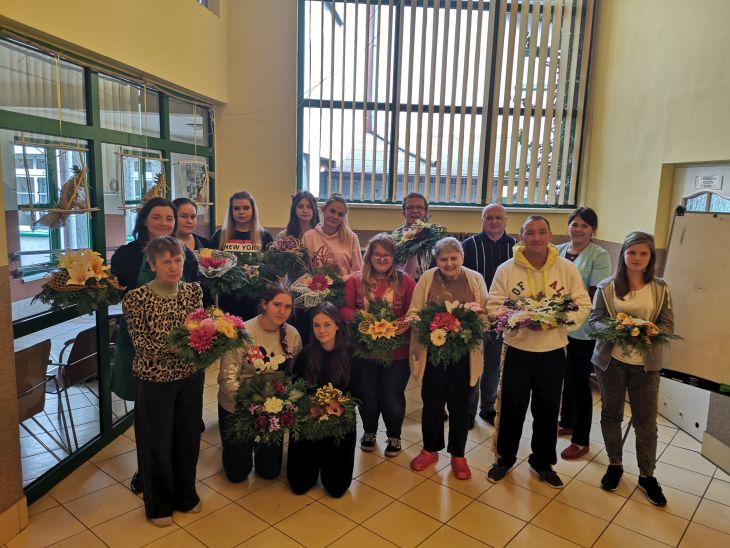 Na zdjęciu mieszkańcy Domu Opieki Społecznej "Opoka" wraz z uczniami z ZSB-C prezentujący gotowe kompozycje kwiatowe.