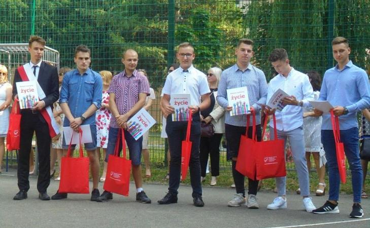 Na zdjęciu została przedstawiona grupa uczniów w galowych strojach. Każdy z nich trzyma dyplom oraz czerwoną torbę, jako podziękowanie za udział w szkolnych akcjach krwodawstwa.
