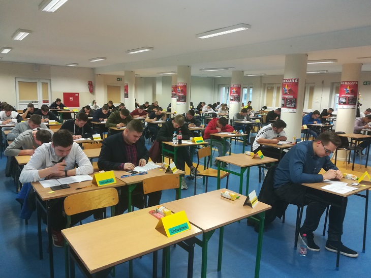 uczniowie siedza przy stołach pisza testy