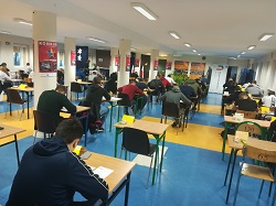 uczniowie siedza przy stołach pisza testy