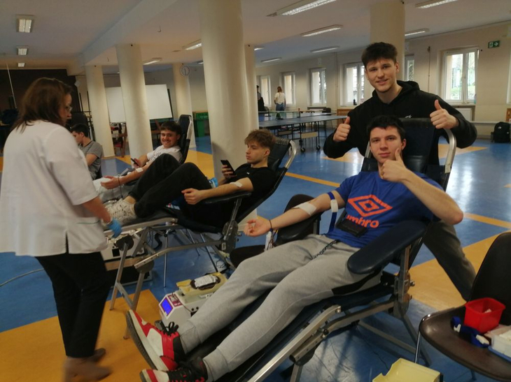 Grupa uczniów podczas oddawania krwi wraz z osobą pobierającą krew
