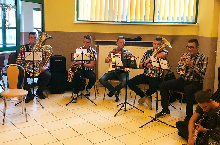 uczniowie siedzą i grają na instrumentach