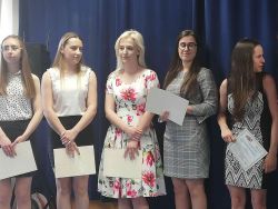 Zdjęcie przedstawia grupę kolorowo ubranych uczennic klas IV na granatowym tle