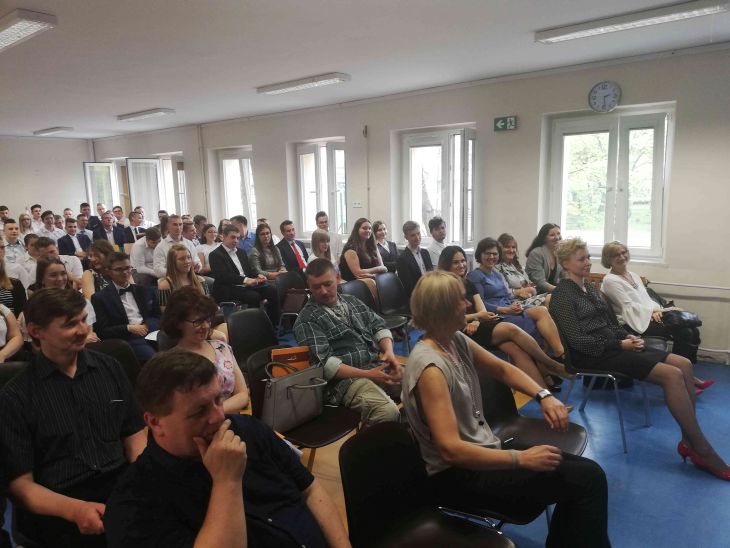 Zdjęcie przedstawia nauczycieli, zaproszonych gości oraz uczniów w auli szkolnej podczas uroczystości zakończenia roku szkolnego klas maturalnych