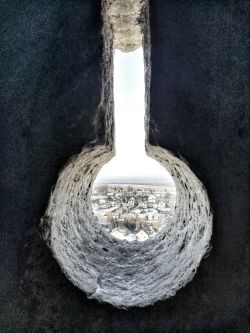 Zdjęciw konkursowe przedstawia otwór strzelniczy, przez który widać panoramę miasta. 