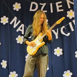 Uczeń grający na gitarze, w tle napis Dzień Nauczyciela