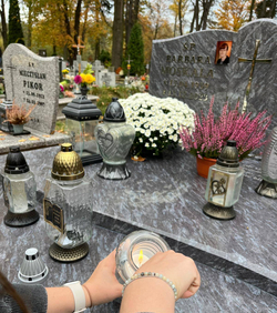 ręce uczennicy zapalającej znicz na grobie jednej z nauczycielek