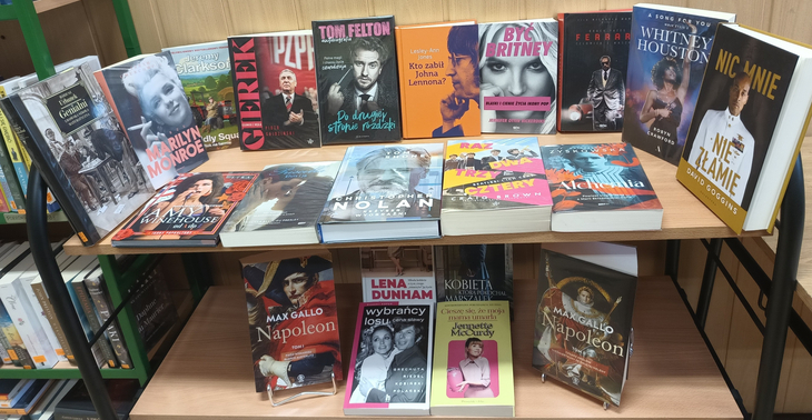 Na zdjęciu widać regał z wyeksponowanymi książkami biograficznymi i autobiograficznymi. Na półkach znajdują się publikacje o znanych postaciach ze świata muzyki, filmu, polityki i historii, ułożone frontami okładek w formie tematycznej wystawy bibliotecznej.